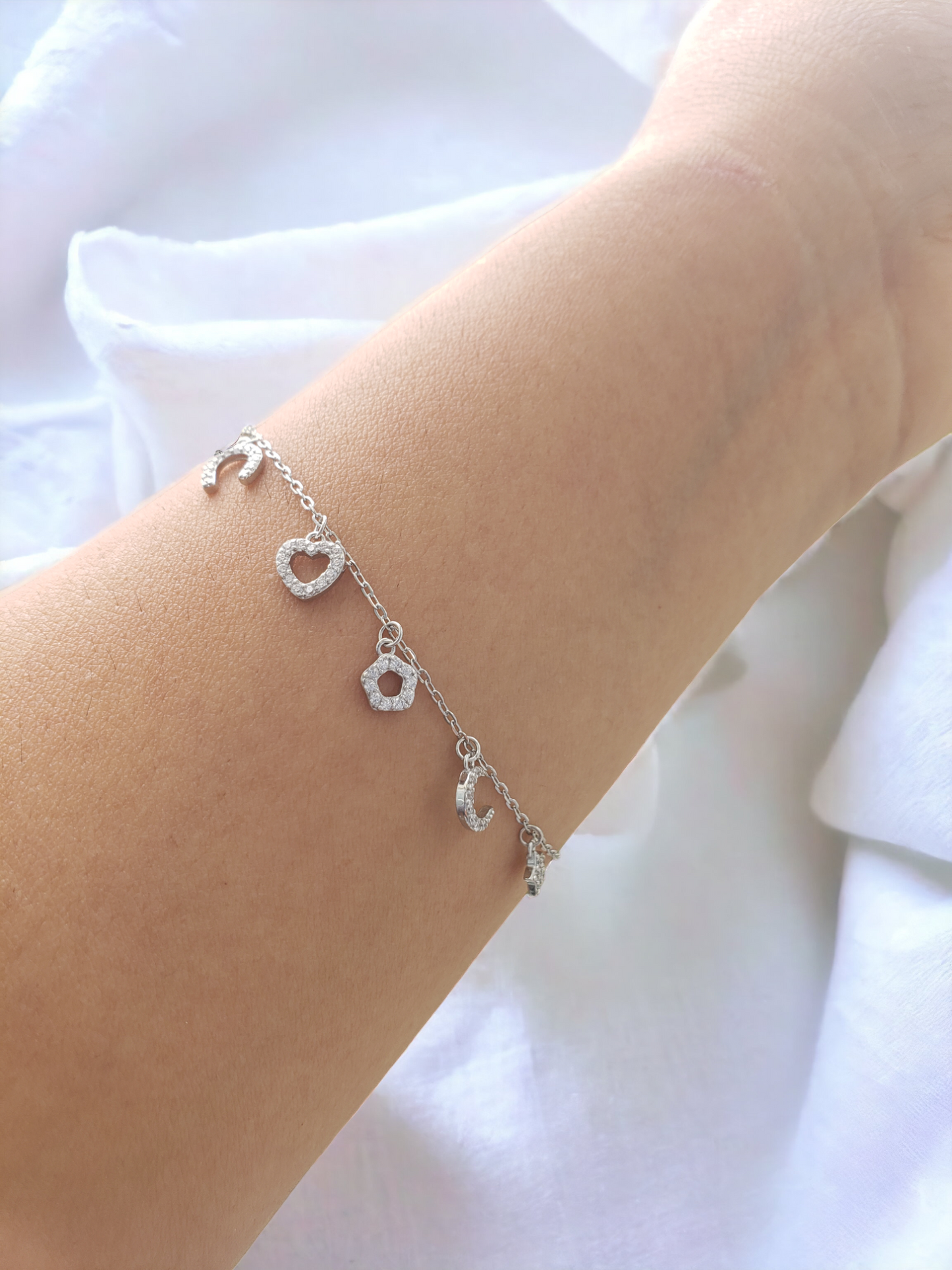 Pulsera con dijes de zirconias. Plata ley 925, acabado en Rodio